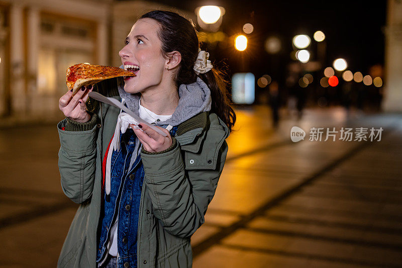 年轻女子在晚上外出时发现了一片美味的披萨