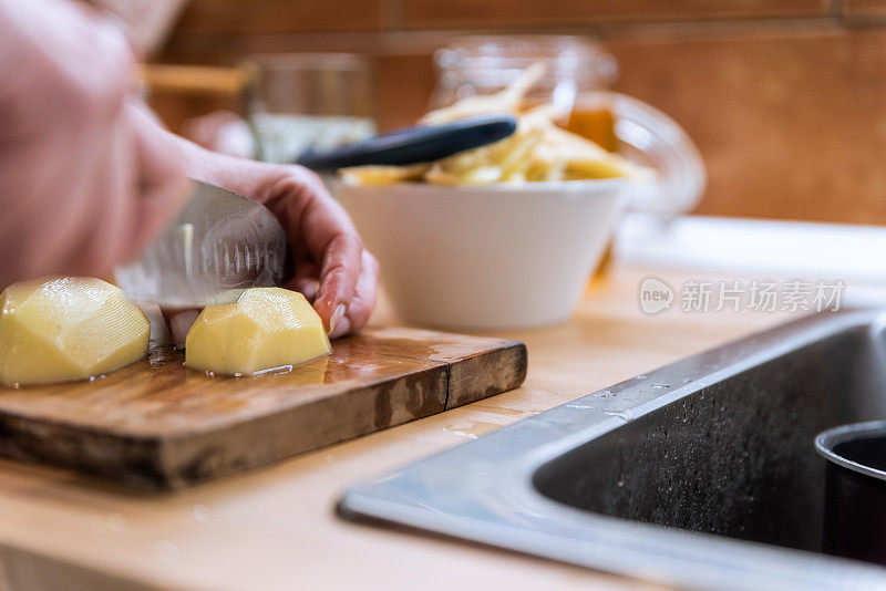 一名妇女在自家厨房里为健康晚餐切土豆