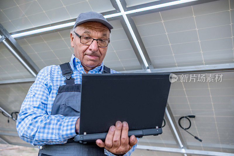 一名技术人员将笔记本电脑放在太阳能电池板下。