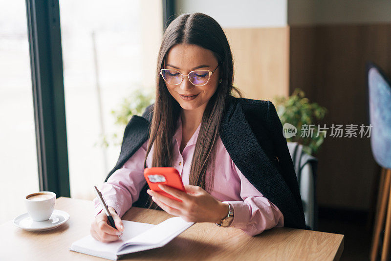 年轻的女商人边打电话边写便条