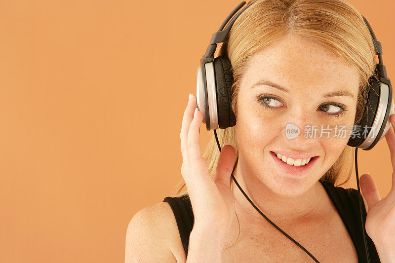 微笑的女人戴着耳机，背景是橙色的