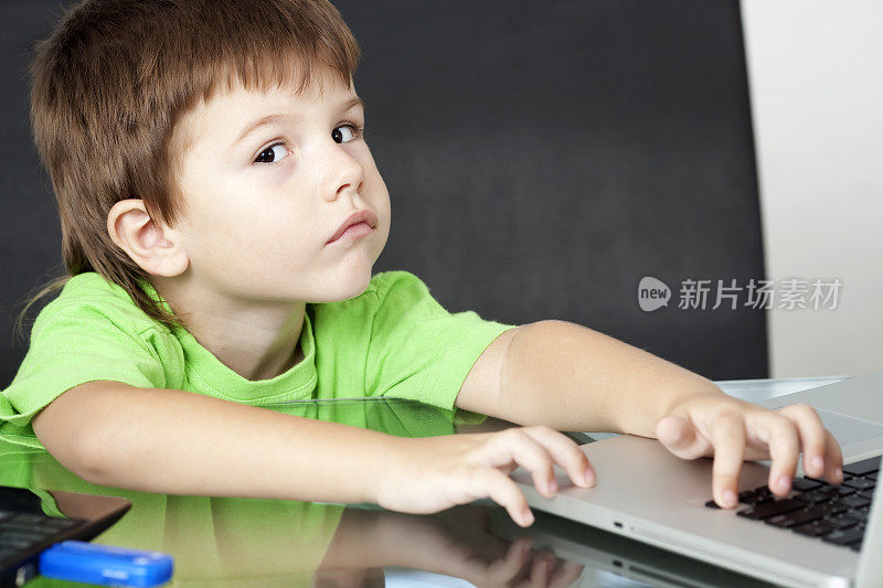 男孩在按笔记本电脑上的按钮。