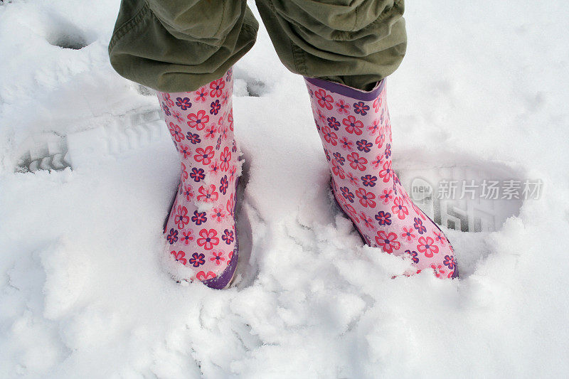 女孩的粉色长筒靴在雪中