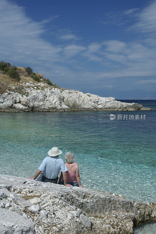 老年夫妇放松地坐在户外看地中海风景