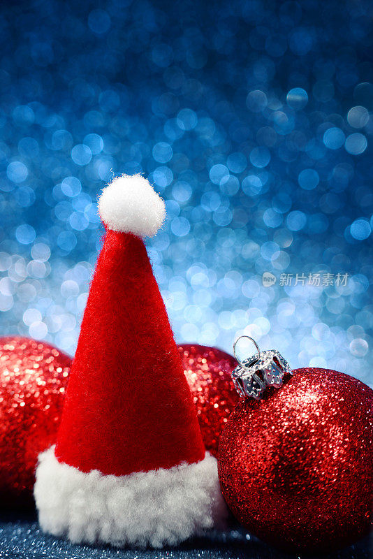 圣诞帽和红色闪亮的圣诞球在蓝色的背景