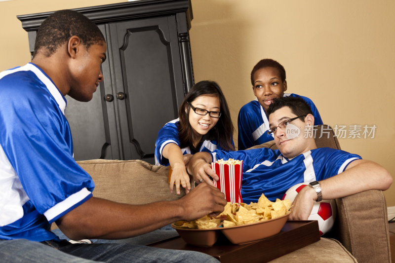 关系:多民族球迷在家吃零食和看电视