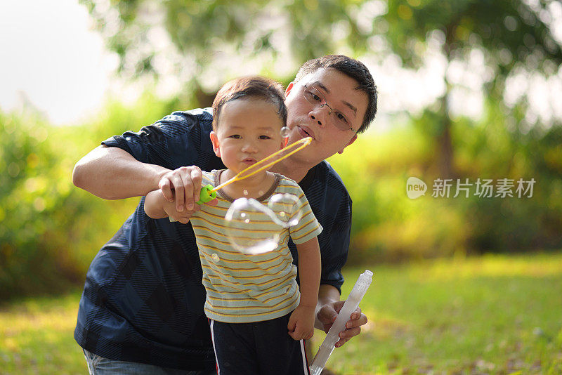 亚洲小孩和父亲玩泡泡棒