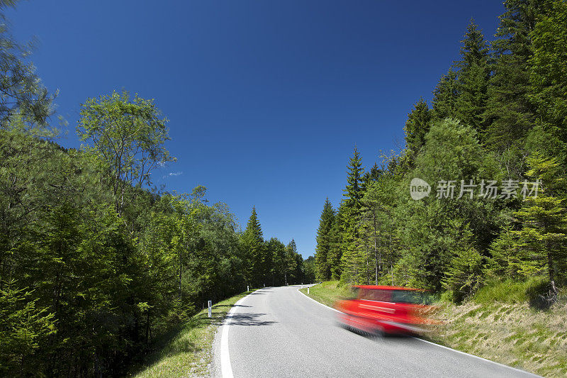 红色汽车行驶在乡村道路上，模糊的运动