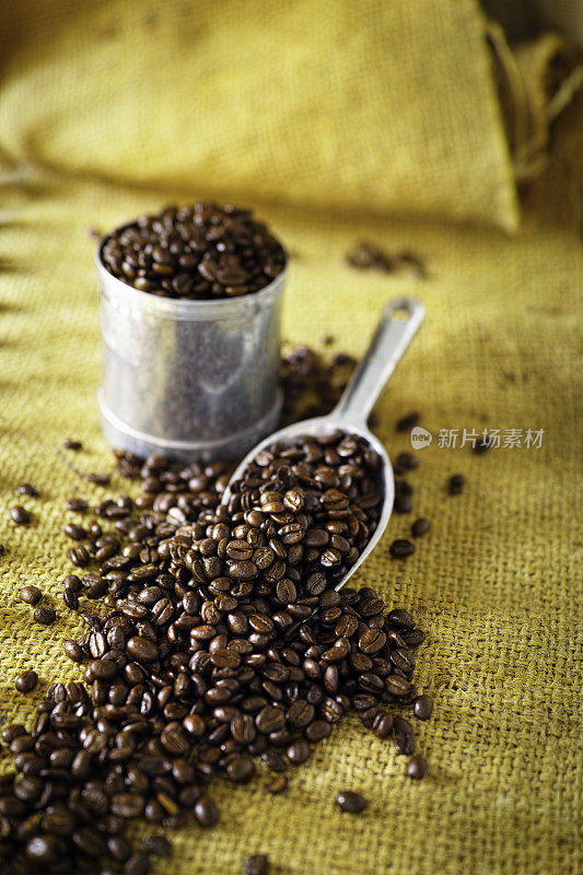 粗麻袋和金属量具的新鲜咖啡豆。