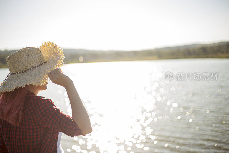 美丽的女人站在户外湖边的木码头上