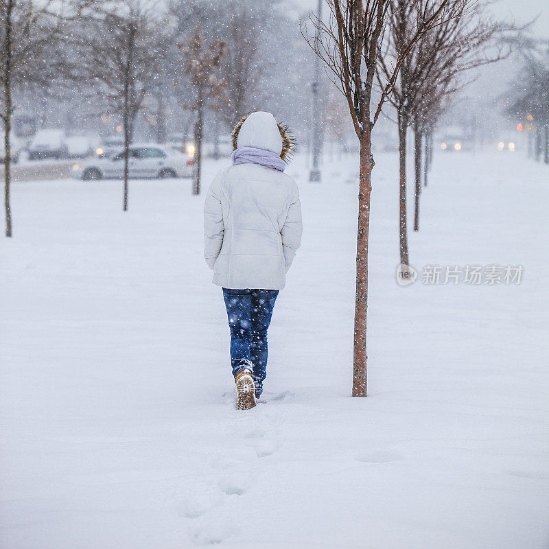 雪下穿着白色夹克的漂亮少女