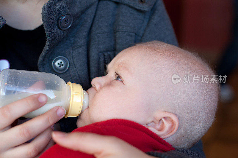 小男孩用妈妈抱着的奶瓶喂奶