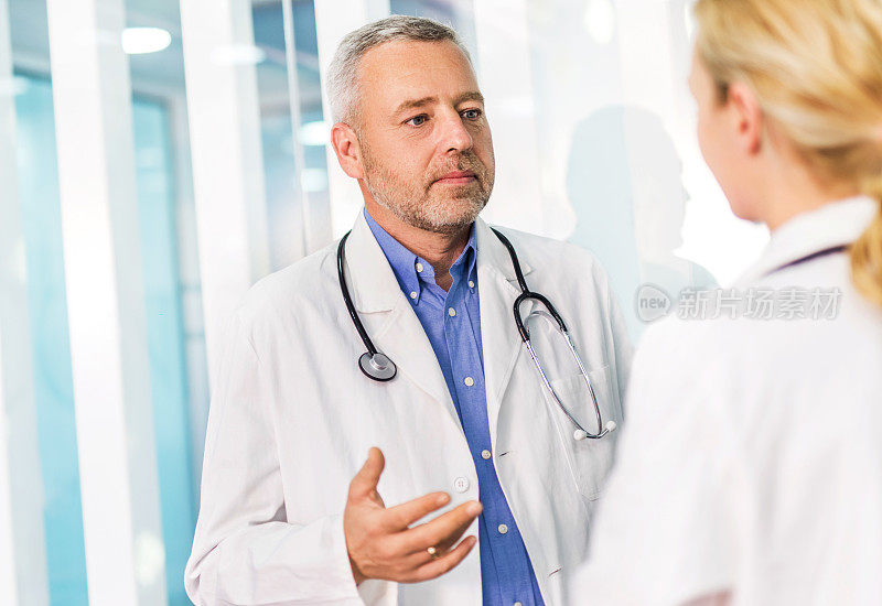 一个成熟的医生在医院和他的女同事聊天。