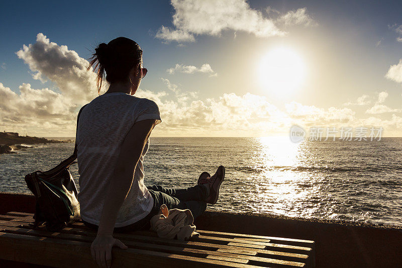 在智利复活节岛上，女孩在海上看日落