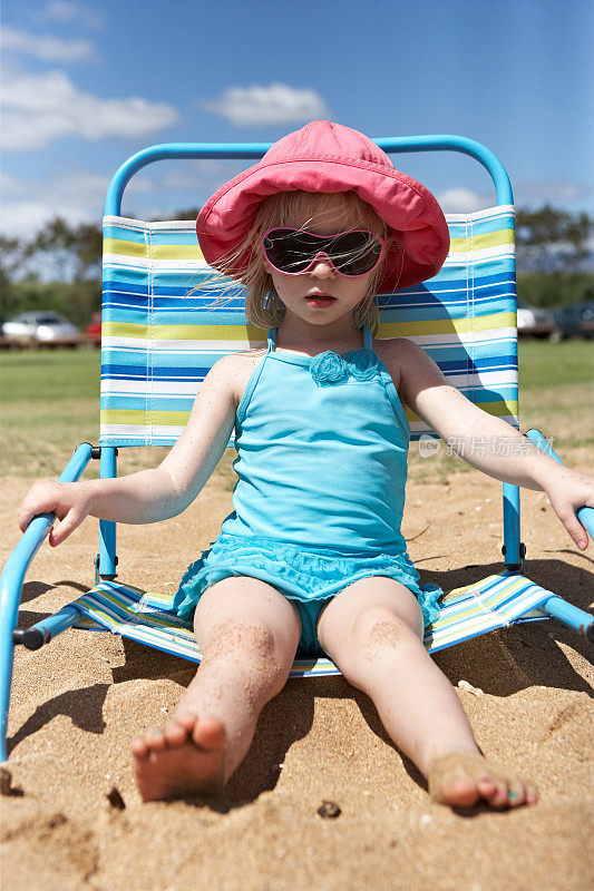 漂亮的小女孩戴着太阳镜在海滩上