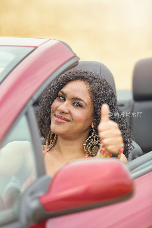 美丽的巴西女人驾驶敞篷车竖起大拇指