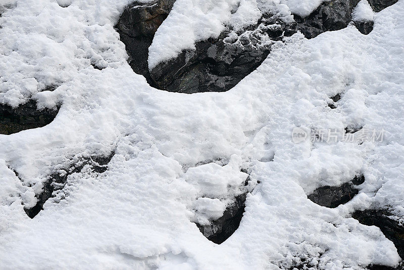 垂直山坡的岩石覆盖着新鲜的雪背景纹理