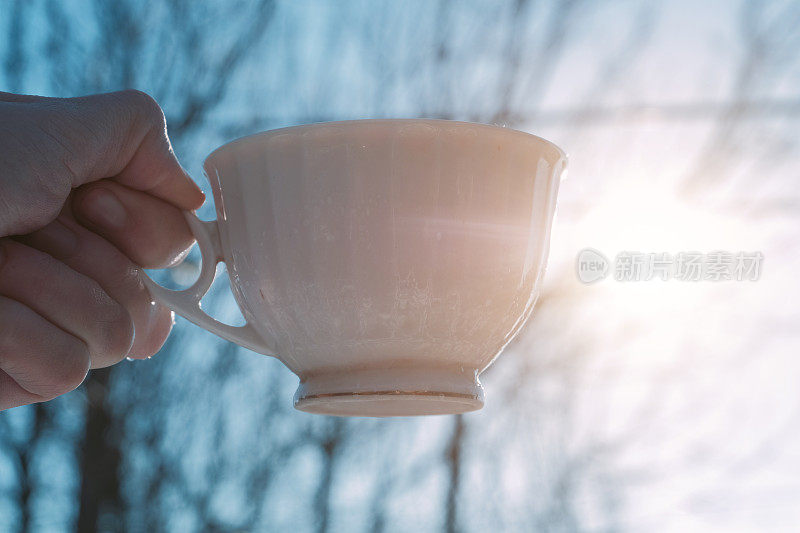 手握一杯咖啡或茶在大自然中