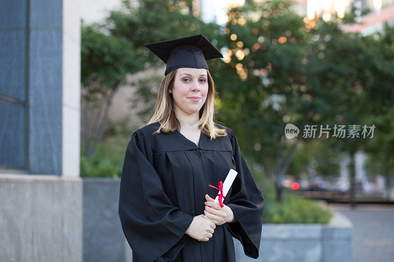 女大学生戴毕业帽，穿着毕业袍，手持毕业证书