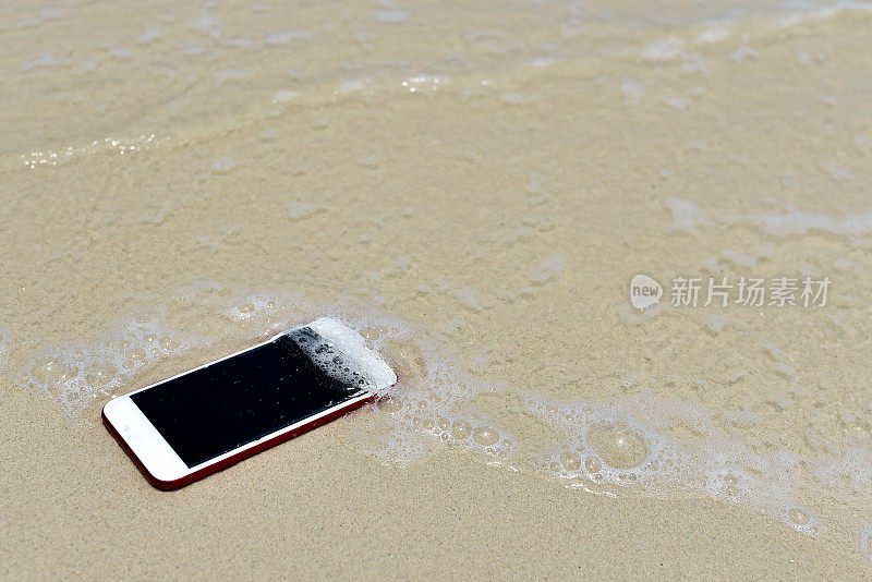 手机丢失。手机掉落消失在海滩上作为背景