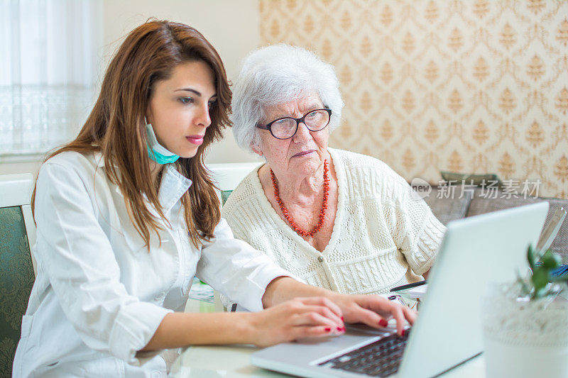 护士和老年病人在笔记本电脑上分析医疗结果。家庭护理的概念。