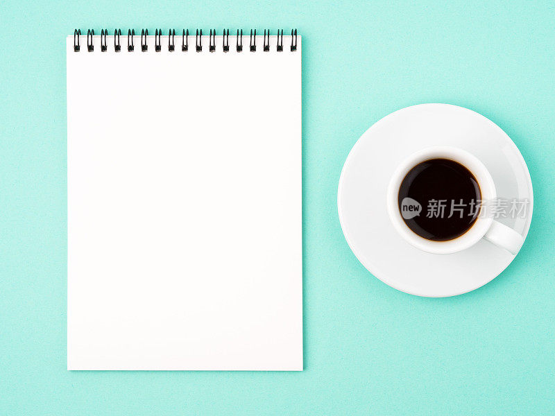 打开空白页的记事本，用来写想法或待办事项，在明亮的蓝色背景上喝杯咖啡