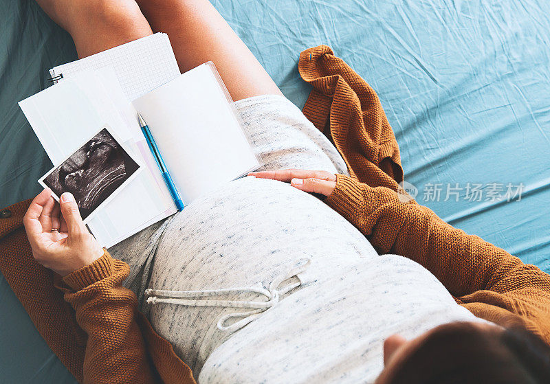 孕妇做笔记，看超声波图像和医疗文件。