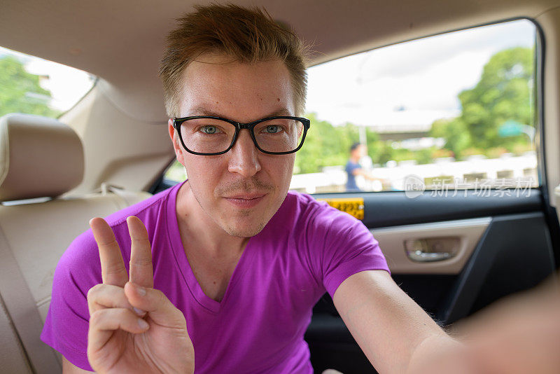车上有一个年轻英俊的男子的肖像，他穿着紫色的衬衫，戴着眼镜