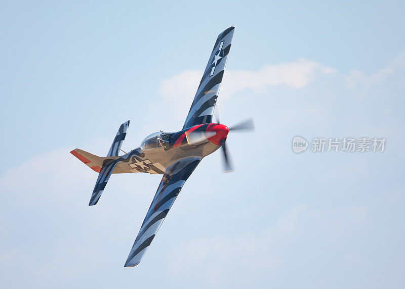 近距离观察P-51D野马(二战美国战斗机)在一个转弯，在多云的天空和美丽的光