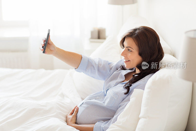 孕妇在家用智能手机自拍