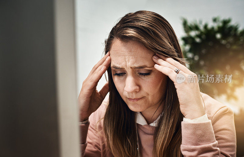 坐在电脑前的金发女人一边担心一边痛苦