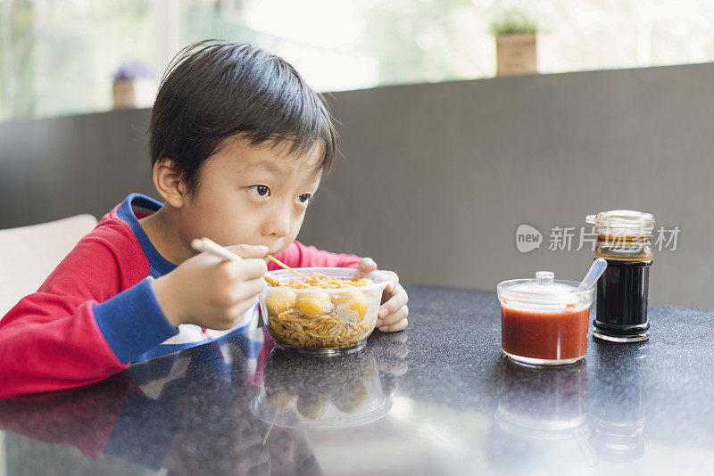 亚洲小孩用筷子吃美味的面条
