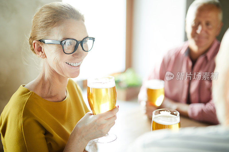 快活的老妇人在酒吧聚会时喝着淡啤酒和朋友聊天
