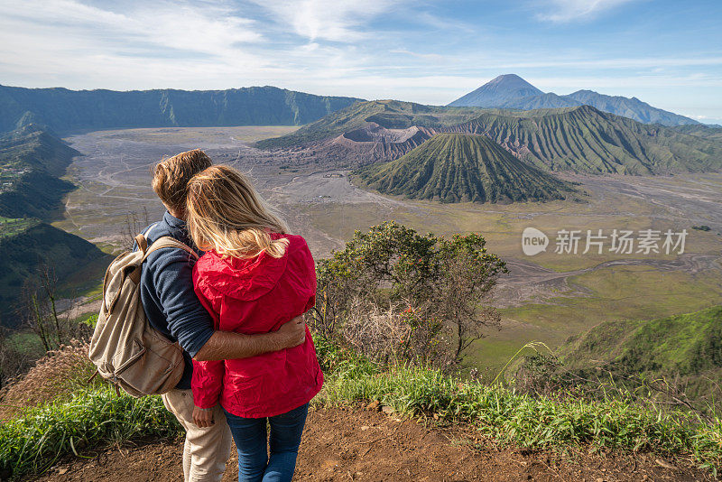 年轻的夫妇徒步旅行沉思火山景观从山顶看布罗莫火山-人们旅行冒险的概念