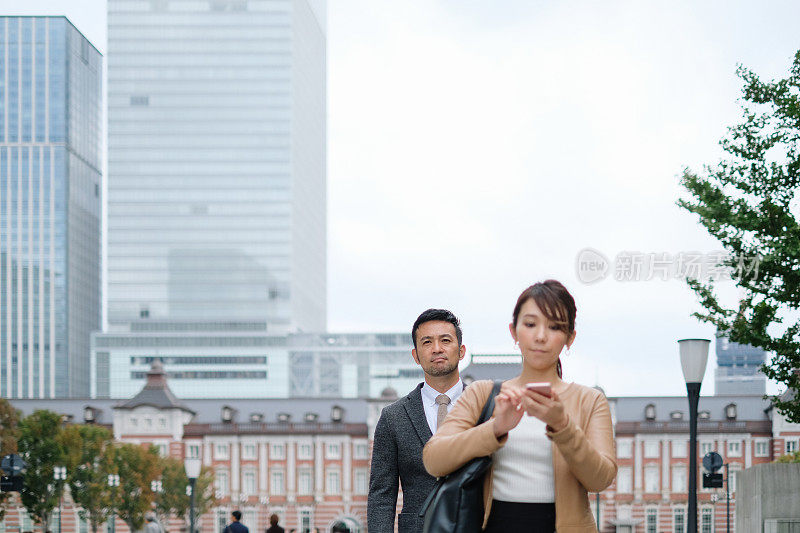 手持智能手机的女商人和自信的商人