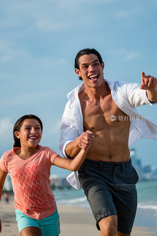 快乐的爸爸和女儿沿着海滩跑着，指着远处