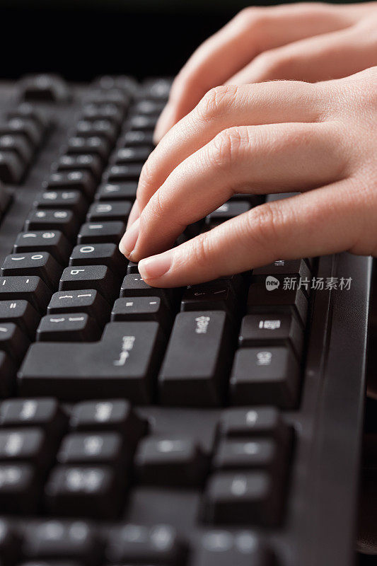 女人的手忙着在黑色的电脑键盘上打字