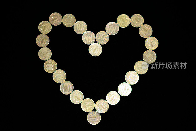 金钱心在黑色的背景上。钱的象征。铜硬币。琐事上。Ten-Ruble硬币。爱钱。繁荣和财富。丰富和繁荣。