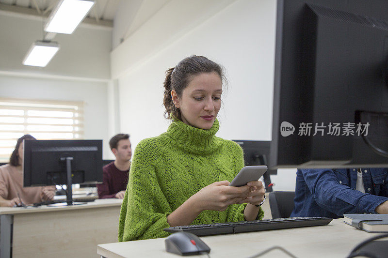 年轻女子在计算机实验室使用手机