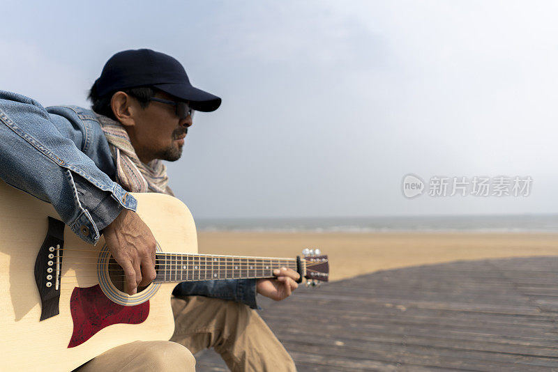 在海滩上弹吉他的男人