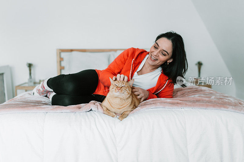 一个年轻女人和她的猫在床上