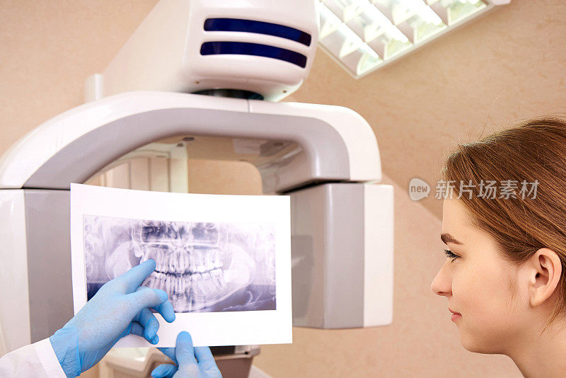 牙科医生在牙科诊所给病人看x光片。牙科的计算机断层摄影术。
