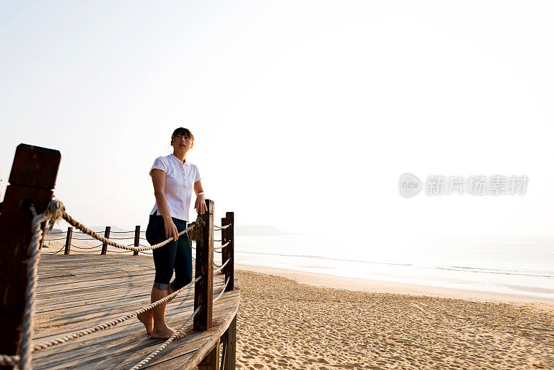 靠在海滩栏杆上的女人