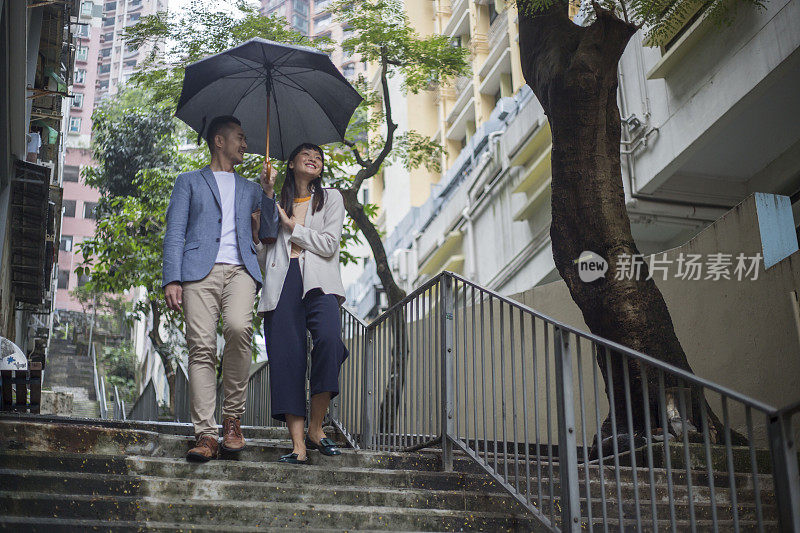年轻的亚洲夫妇撑着雨伞漫步香港