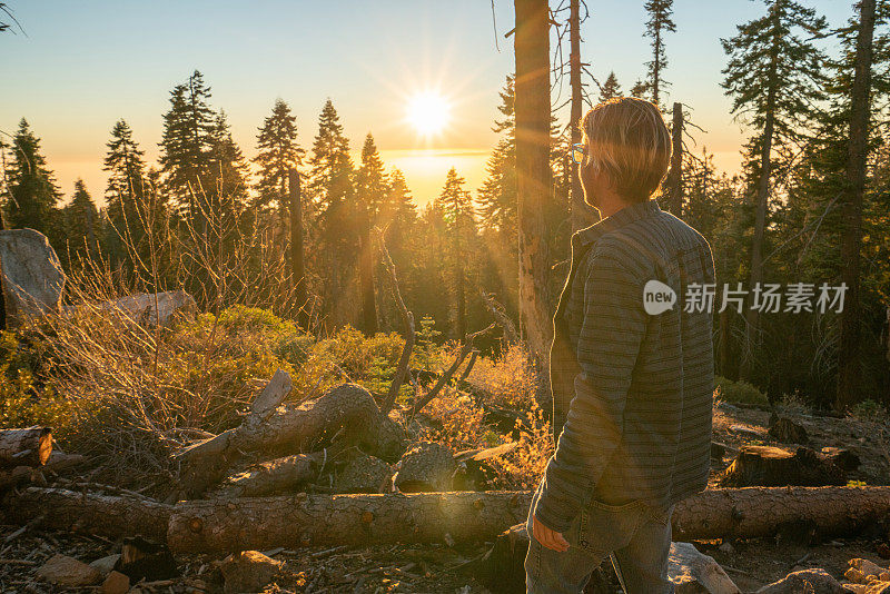 一个年轻人站在森林里看日落时美丽的山谷