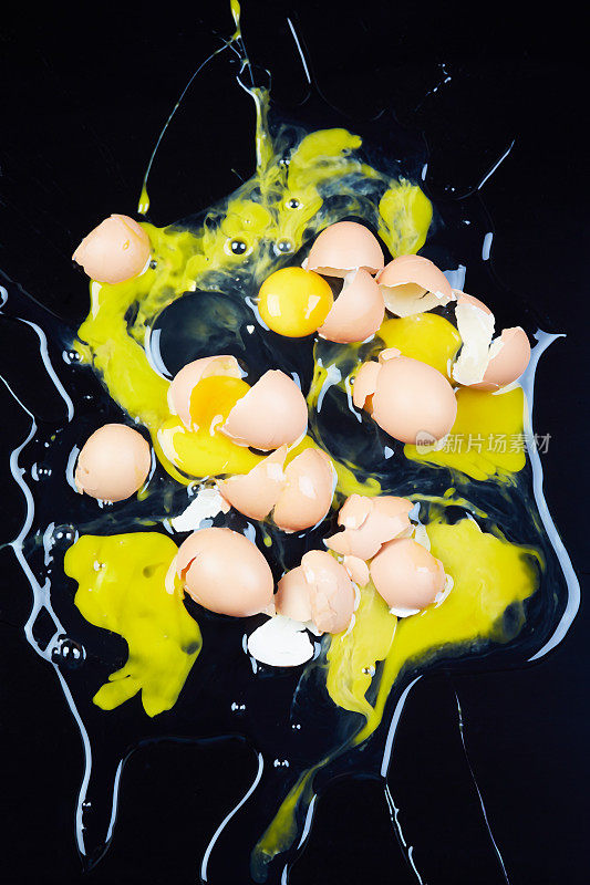 许多碎鸡蛋滴在闪亮的黑色背景上