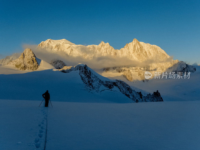 在积雪的斜坡上爬山。瑞士阿尔卑斯山。欣赏日出