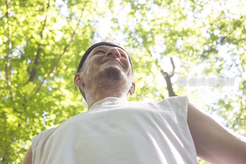 英俊的成年男子准备在阳光明媚的夏日在森林里跑步锻炼