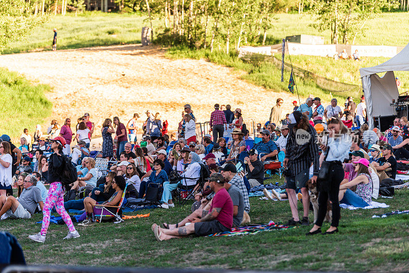 斯诺马斯村和人们坐在滑雪坡草地上听免费音乐会