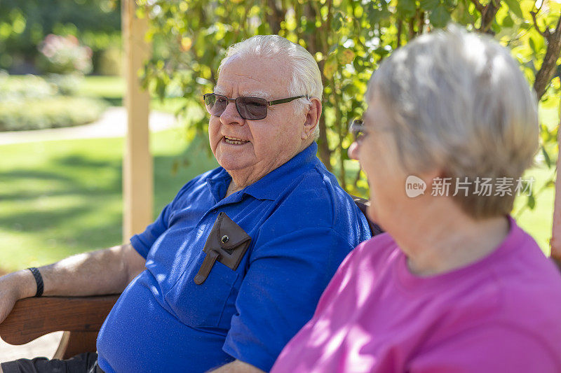 一对老年夫妇坐在公园长椅上聊天